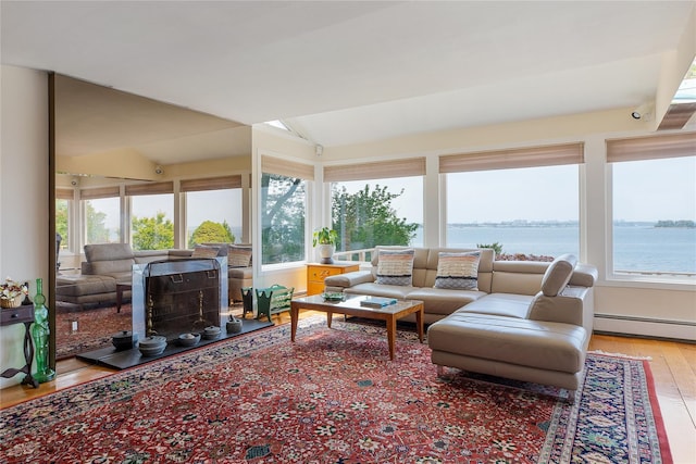 sunroom / solarium with a water view, a baseboard radiator, a fireplace, and vaulted ceiling