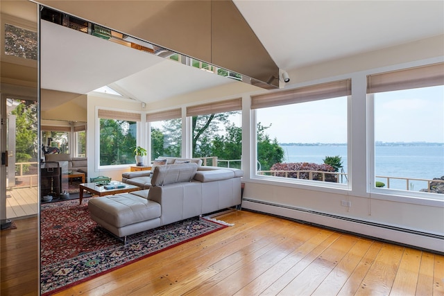 sunroom featuring lofted ceiling, a healthy amount of sunlight, a baseboard radiator, and a water view