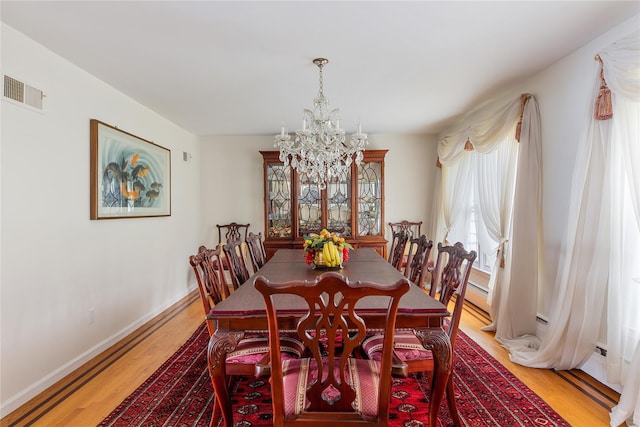 dining room with light wood-type flooring, visible vents, a notable chandelier, and baseboards