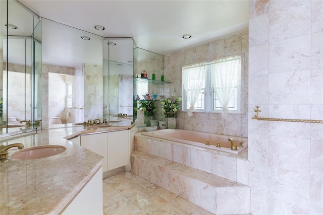 bathroom with two vanities, a sink, tile walls, and a bath