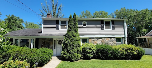 view of front of home featuring stone siding, a chimney, and a front lawn