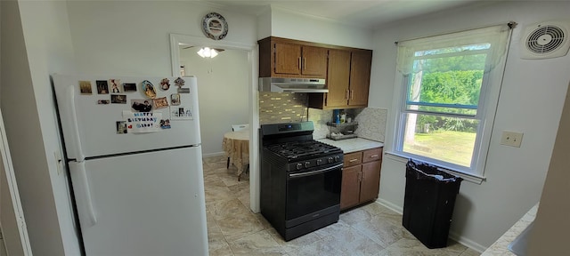 kitchen with light countertops, backsplash, freestanding refrigerator, black gas stove, and extractor fan