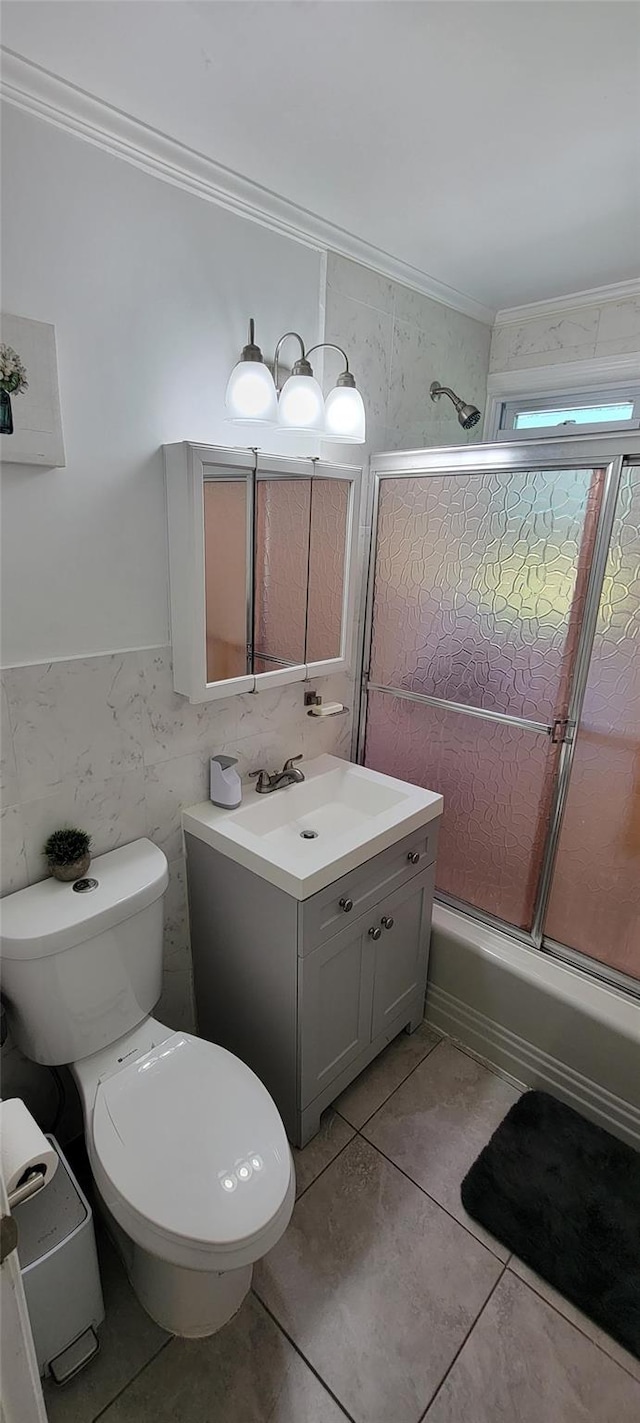 bathroom with toilet, enclosed tub / shower combo, crown molding, vanity, and tile walls