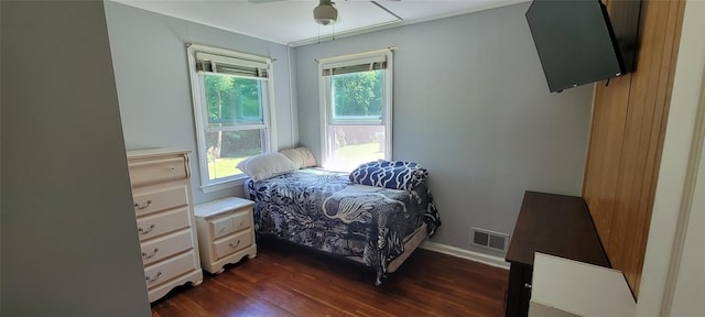 bedroom with dark wood-style floors, multiple windows, visible vents, and baseboards