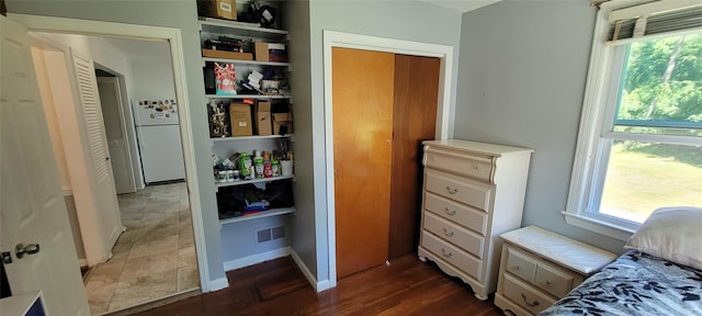 bedroom with dark wood-style floors, freestanding refrigerator, visible vents, and baseboards