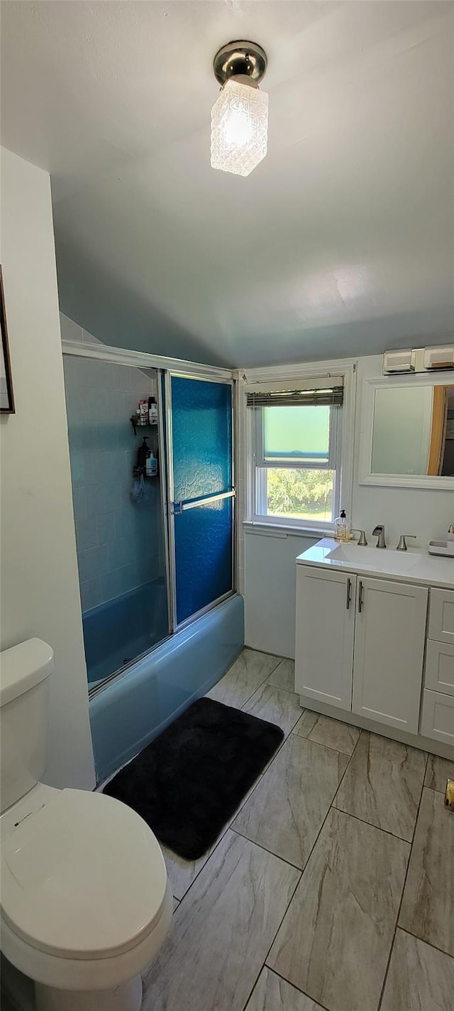 bathroom with marble finish floor, vanity, toilet, and bath / shower combo with glass door