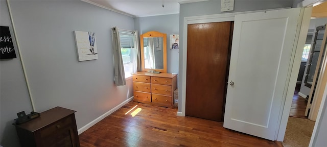 bedroom with crown molding, baseboards, and wood finished floors