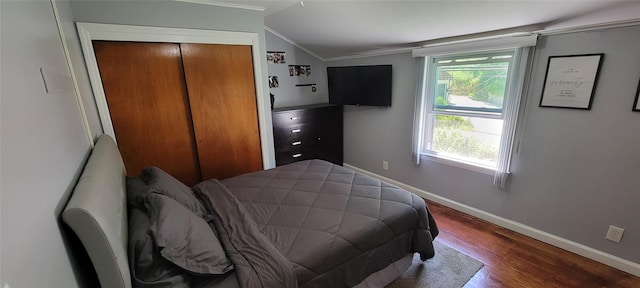 bedroom with baseboards, ornamental molding, wood finished floors, vaulted ceiling, and a closet