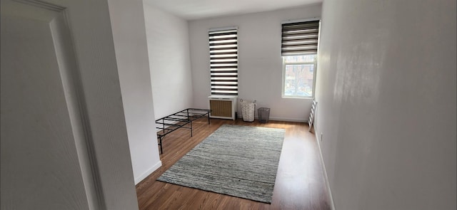 spare room with radiator, baseboards, and wood finished floors