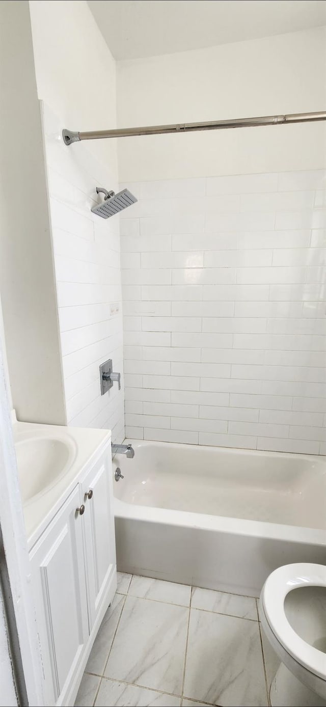 bathroom featuring toilet, marble finish floor, vanity, and bathing tub / shower combination