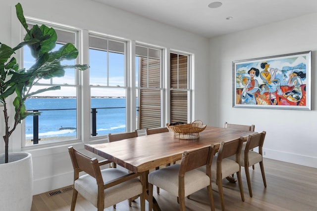 dining area with light wood-style floors, visible vents, and baseboards