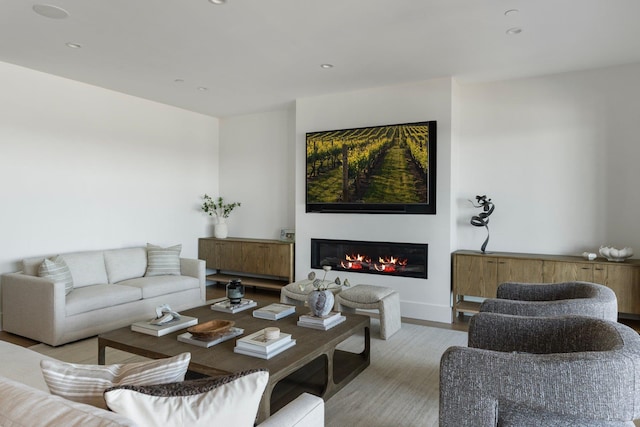 living area featuring light wood-style floors, a glass covered fireplace, and recessed lighting