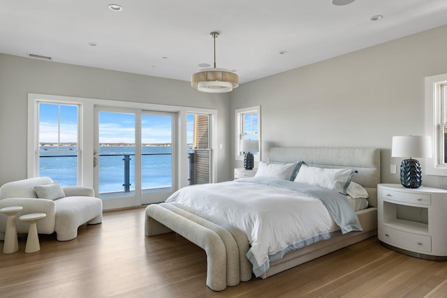 bedroom featuring visible vents, light wood-style flooring, a water view, access to exterior, and recessed lighting