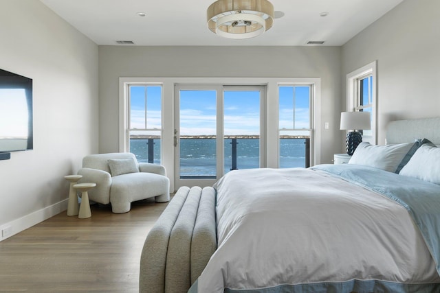 bedroom with access to outside, visible vents, baseboards, and wood finished floors