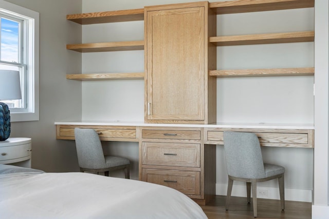 bedroom featuring built in desk and wood finished floors