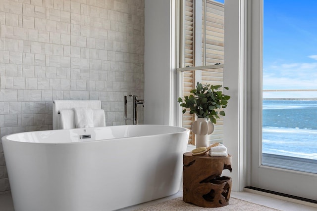 bathroom with a freestanding tub and tile walls