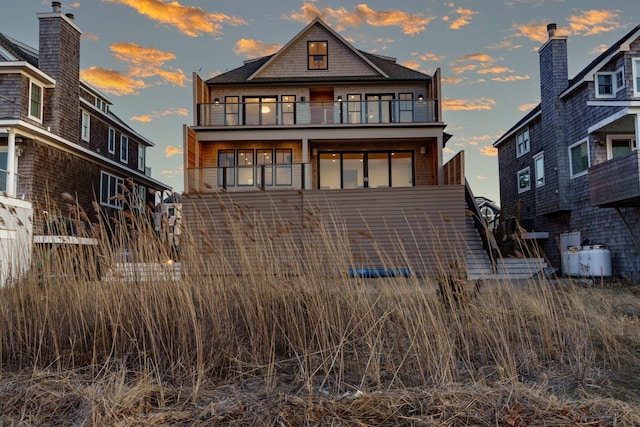 back of house at dusk with a balcony