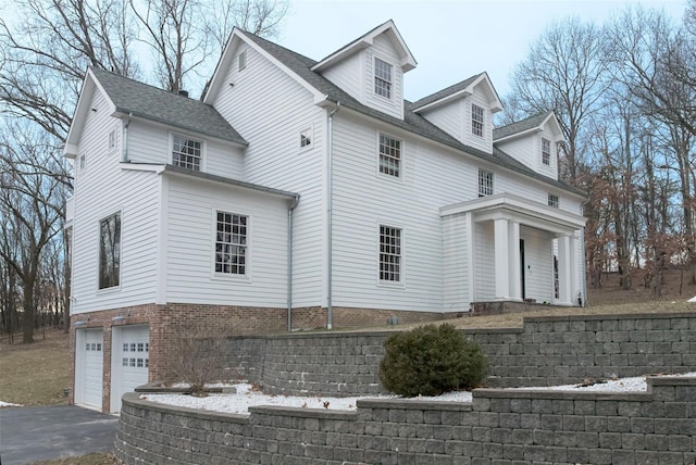 view of side of property featuring aphalt driveway and an attached garage