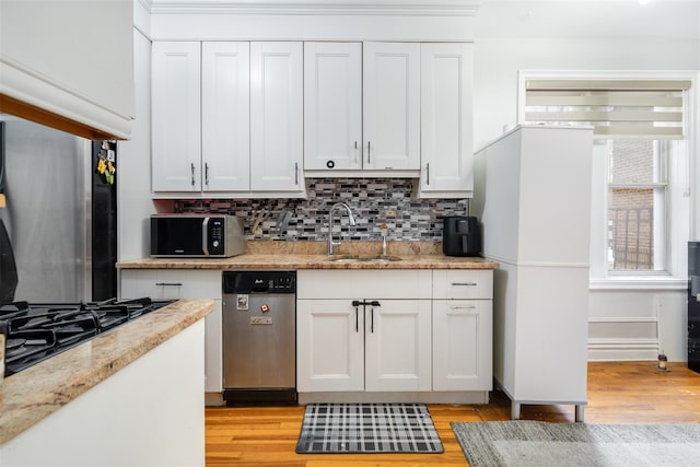 kitchen with black gas cooktop, light wood-style floors, white cabinets, and a sink