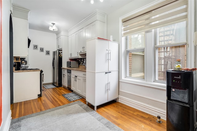 kitchen with appliances with stainless steel finishes, white cabinets, backsplash, and light wood finished floors