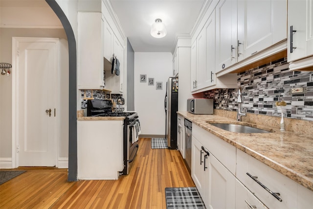 kitchen featuring light wood-style floors, appliances with stainless steel finishes, white cabinets, and a sink