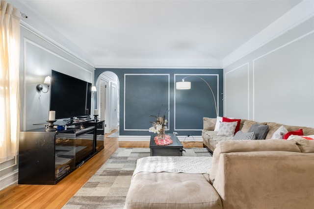 living area featuring light wood-style flooring, arched walkways, and a decorative wall