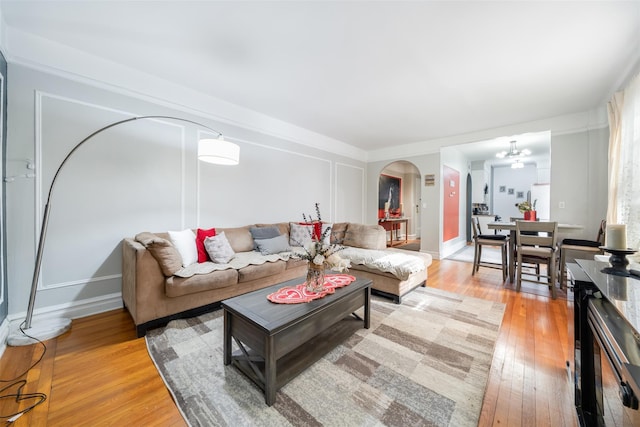 living room featuring light wood-style floors, baseboards, and arched walkways