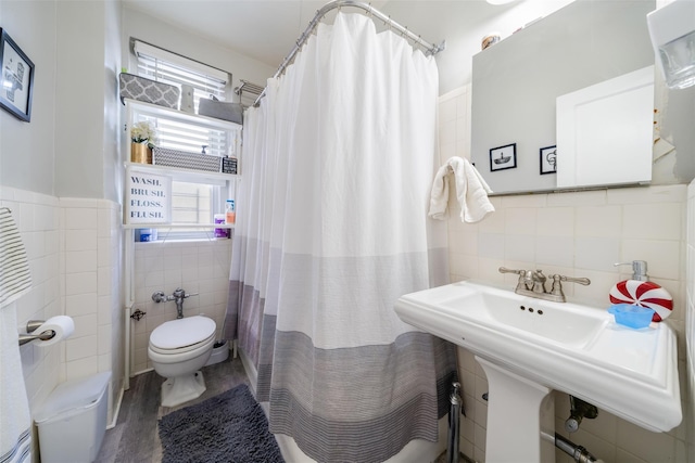 bathroom with toilet, a sink, tile walls, and a shower with shower curtain