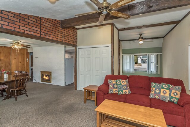 carpeted living area with a fireplace, beamed ceiling, brick wall, and ceiling fan