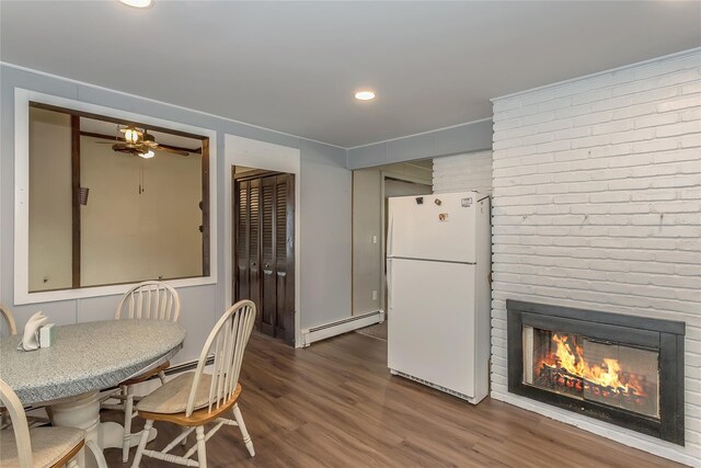 dining area with a fireplace, a baseboard radiator, recessed lighting, a ceiling fan, and wood finished floors