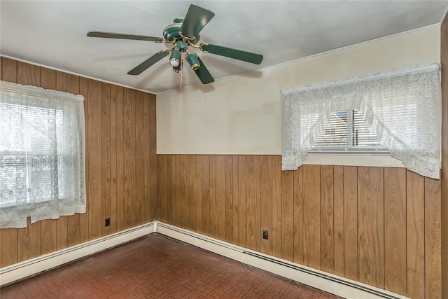 unfurnished room featuring a wealth of natural light, wood walls, and a baseboard radiator