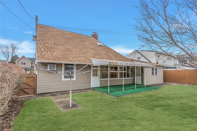 back of property with a yard, roof with shingles, a chimney, and fence