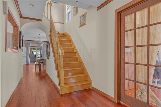 stairs with wood-type flooring, baseboards, and crown molding