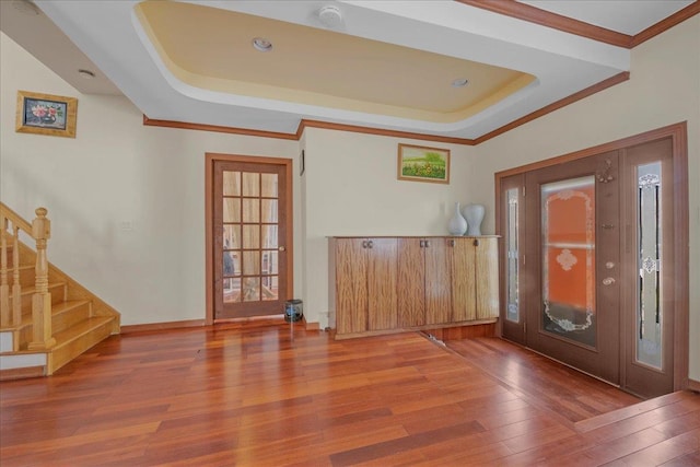 entryway featuring wood finished floors, baseboards, stairs, ornamental molding, and a raised ceiling