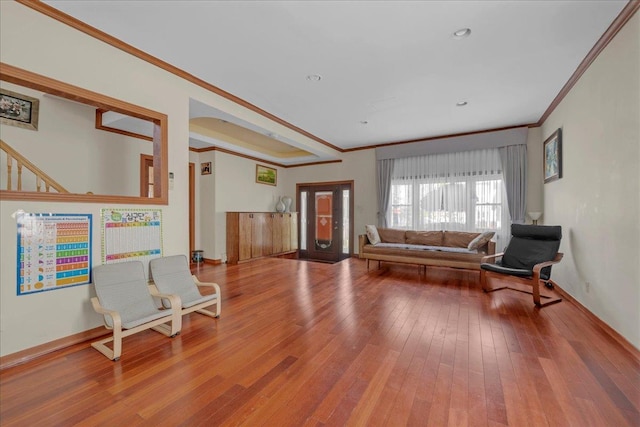 living area with wood-type flooring, crown molding, and baseboards