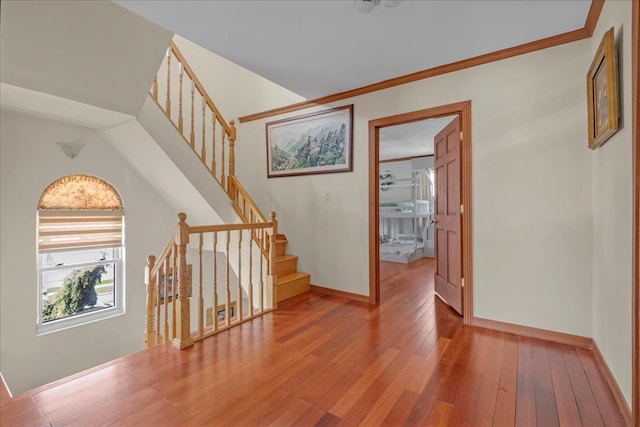 interior space with crown molding, stairway, hardwood / wood-style flooring, and baseboards