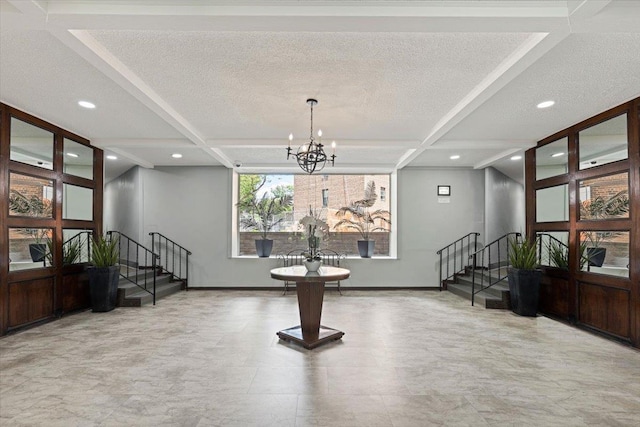 foyer entrance with stairs, a textured ceiling, baseboards, and a notable chandelier