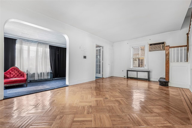 interior space with arched walkways, a wall mounted AC, stairs, and baseboards