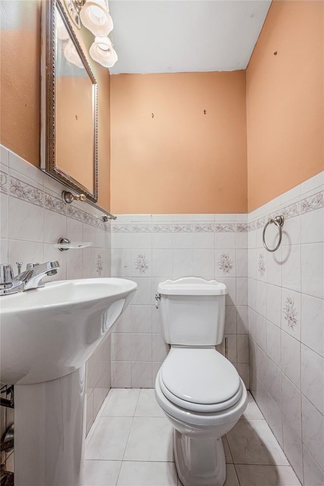 half bathroom with wainscoting, toilet, and tile patterned floors