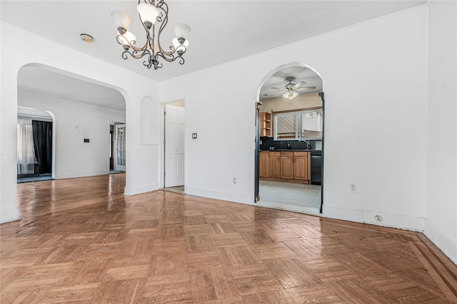 unfurnished room with arched walkways, ceiling fan with notable chandelier, and baseboards