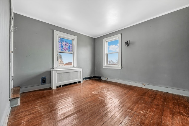 spare room with ornamental molding, radiator, wood-type flooring, and baseboards