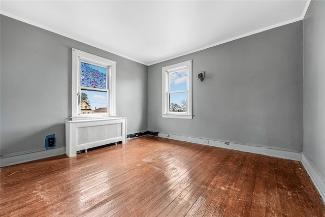 unfurnished room featuring radiator heating unit, hardwood / wood-style flooring, and crown molding