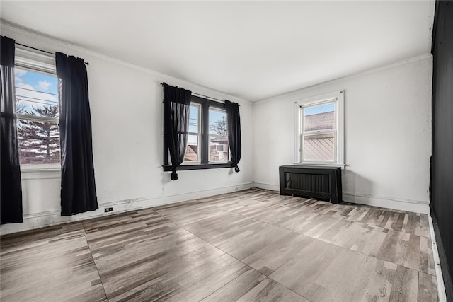 spare room featuring crown molding, baseboards, and wood finished floors