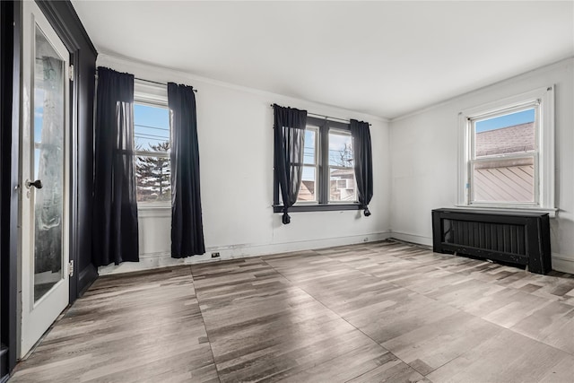 spare room with light wood-type flooring, radiator heating unit, and plenty of natural light