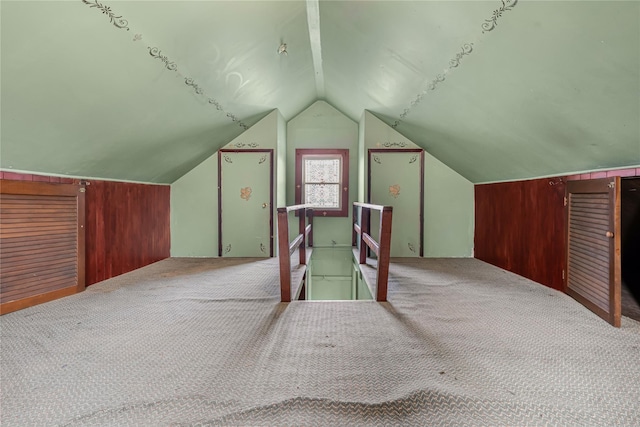 additional living space featuring wooden walls, vaulted ceiling, and carpet flooring