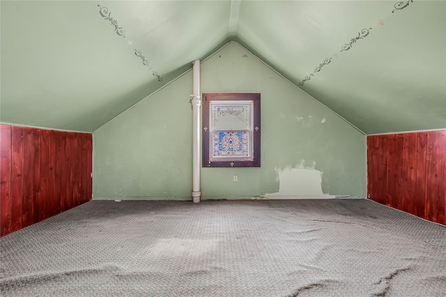 additional living space featuring vaulted ceiling, carpet floors, and wood walls