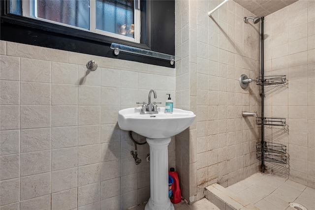 full bath with a sink, tile walls, and tiled shower