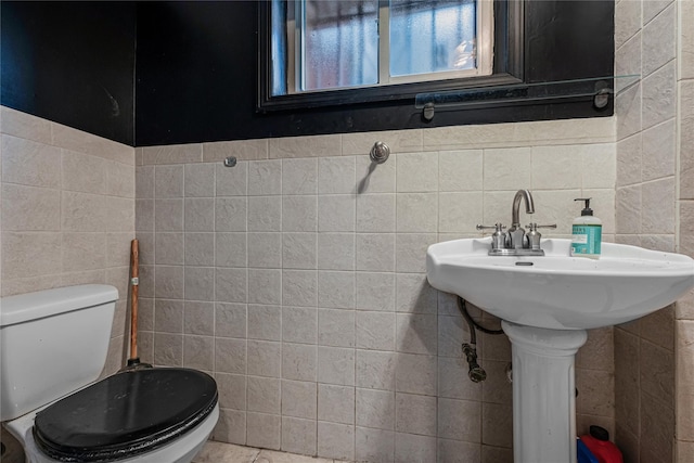 half bath featuring toilet and tile walls