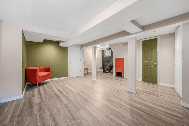 finished basement with stairway, recessed lighting, light wood-style flooring, and baseboards