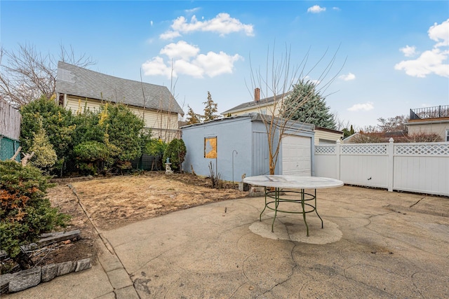 view of patio featuring a garage, fence, and an outbuilding